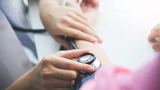 Asian Female doctor measuring blood pressure of a 